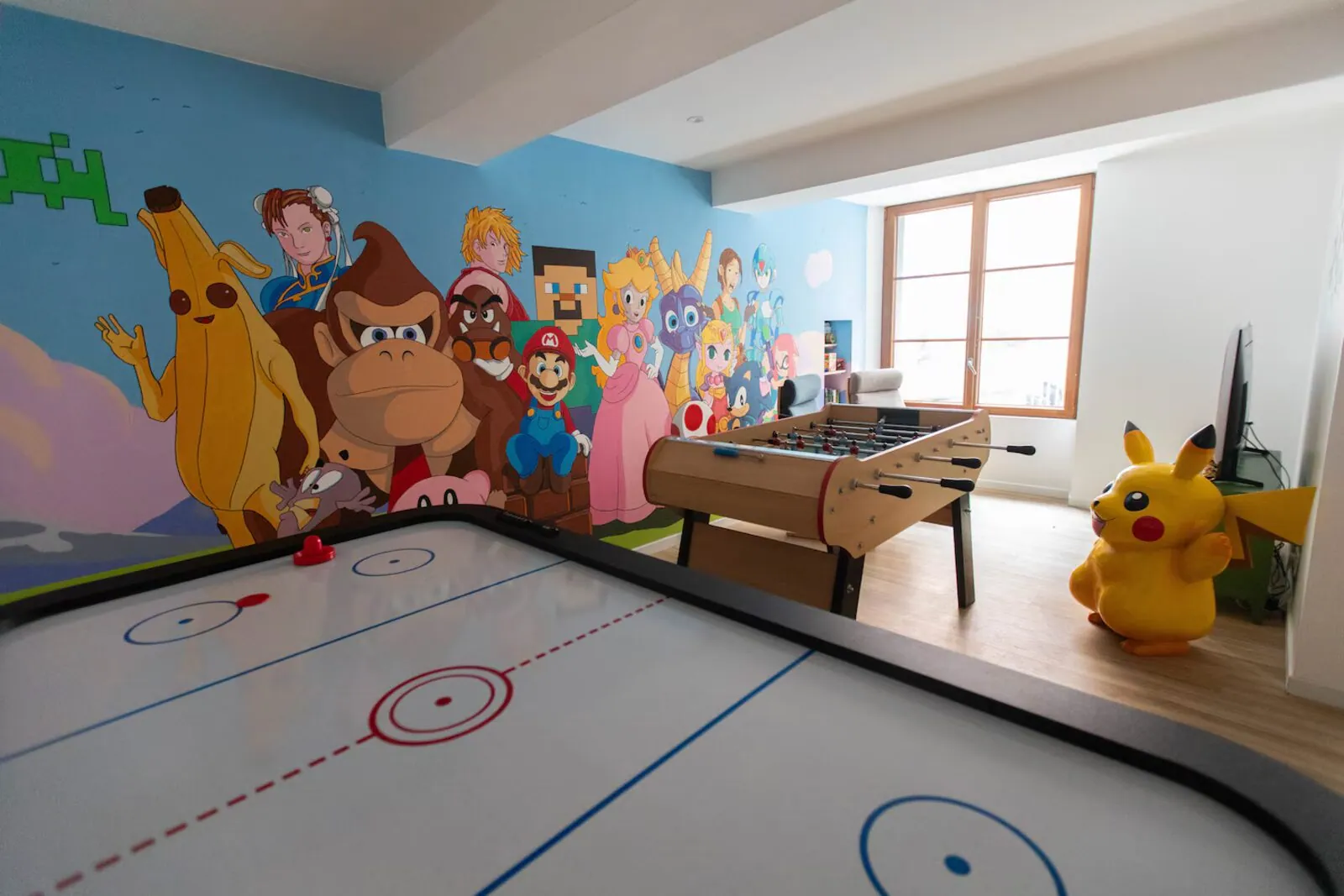 Salle Chill & Play : air hockey, baby-foot et fresque personnages – grand gîte gaming Var